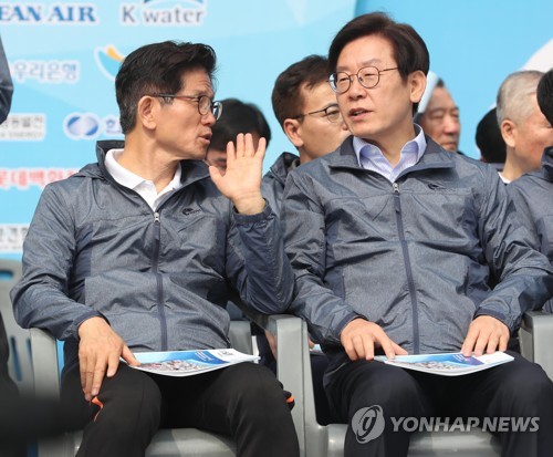 This file photo, taken May 1, 2018, shows Democratic Party presidential candidate Lee Jae-myung (R) and People Power Party presidential candidate Kim Moon-soo speaking as they attend a marathon event in Seoul. (Yonhap)