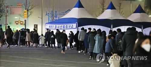 Des personnes font la queue pour subir un test de dépistage du nouveau coronavirus (Covid-19) dans un centre provisoire installé au parc olympique à Songpa, dans le sud-est de Séoul, le soir du mercredi 8 décembre 2021. 