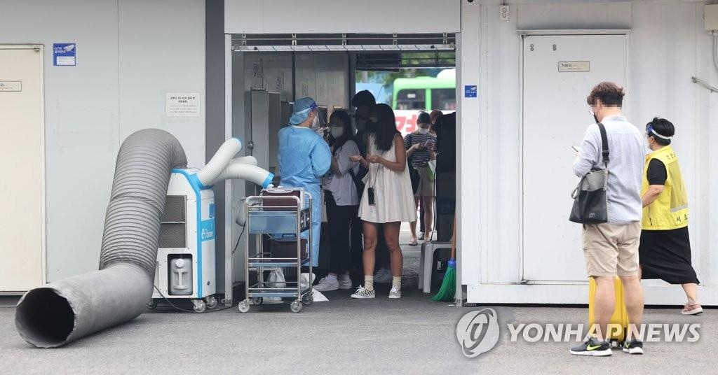 Des personnes font la queue avant de se soumettre à un test de dépistage du Covid-19 dans un centre provisoire situé dans une gare routière du sud de Séoul, le 27 juillet 2022.