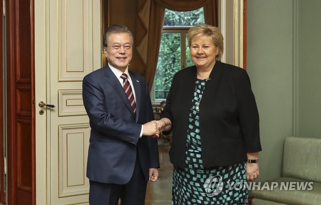 握手する文大統領（左）とソルベルグ首相＝１３日、オスロ（聯合ニュース）