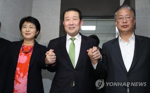 合併で合意し、手を握り合う３党の幹部＝１４日、ソウル（聯合ニュース）