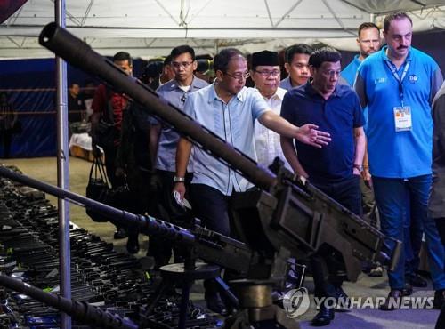 두테르테 필리핀 대통령이 최대 이슬람 반군 MILF가 반납한 무기를 살펴보고 있다