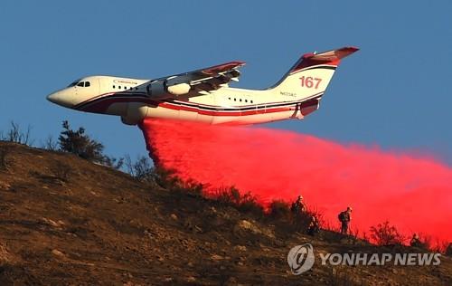 31일 미 캘리포니아 샌버나디노의 힐사이드 파이어 화재 현장 주변에서 항공기가 방화제를 살포하고 있다. [AFP=연합뉴스]