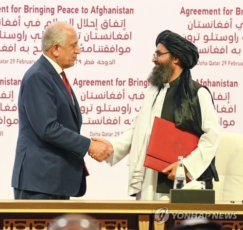 지난해 2월 29일 카타르 도하에서 미국과의 평화협상서에 서명한 후 잘메이 할릴자드 미국 아프간 특사와 악수를 하는 물라 압둘 가니 바라다르(오른쪽). [EPA=연합뉴스]