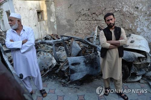 미군 드론 폭격받은 차량 잔해 앞에 선 유족