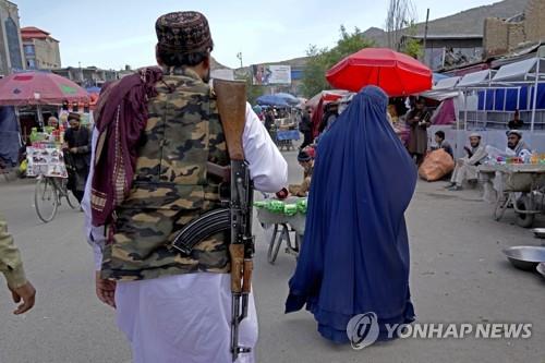 아프간 카불에서 탈레반 대원(왼쪽) 옆으로 부르카를 착용하고 걷는 여성