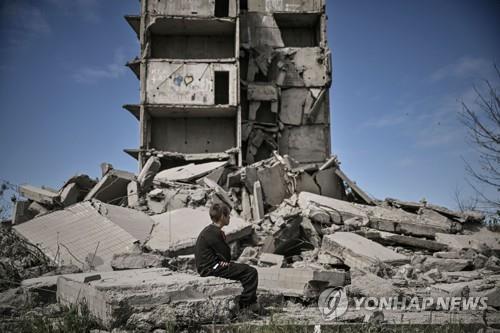 러시아의 포격으로 파괴된 크라마토르스크 시의 건물 앞에 앉아 있는 소년