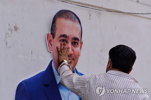 인도의 보석재벌 니라브 모디의 사진에 손을 대고 있는 인도 시민.