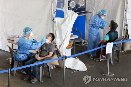 Unos comerciantes del mercado tradicional Garak, en Seúl, son sometidos a exámenes del coronavirus, el 27 de septiembre de 2021, luego de que se reportara una infección masiva en el mercado. 