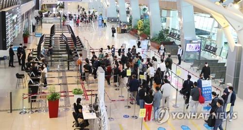 Los pasajeros esperan en fila para obtener sus tarjetas de embarque, el 15 de octubre de 2021, en el Aeropuerto Internacional de Gimpo, para abordar un vuelo hacia la isla turística de Jeju, en el sur del país, mientras el Gobierno anunció reglas de distanciamiento social aliviadas que serán aplicadas durante las dos semanas siguientes.