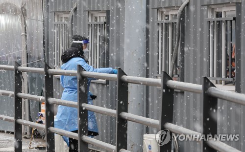 La foto, tomada el 20 de enero de 2022, muestra a un trabajador sanitario ingresando en una cabina de contenedor, en una clínica provisional instalada para las pruebas del COVID-19, frente a la Estación de Seúl, en el centro de la capital surcoreana. 