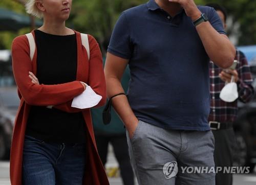 En la fotografía de archivo, las personas sostienen mascarillas de protección sanitaria mientras caminan por una calle de Seúl, el 26 de septiembre de 2022, a medida que el Gobierno retiró su uso obligatorio al aire libre.