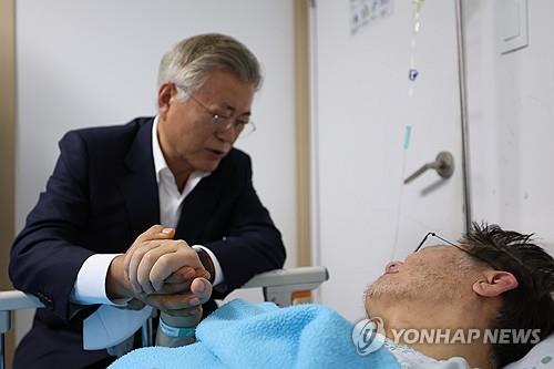 El expresidente Moon Jae-in (izda.) sostiene la mano del líder del principal opositor Partido Democrático, Lee Jae-myung, el 19 de septiembre de 2023, durante su visita en un hospital. Moon pidió a Lee que ponga fin a su huelga de hambre, iniciada hace casi tres semanas, en contra de las políticas del Gobierno.