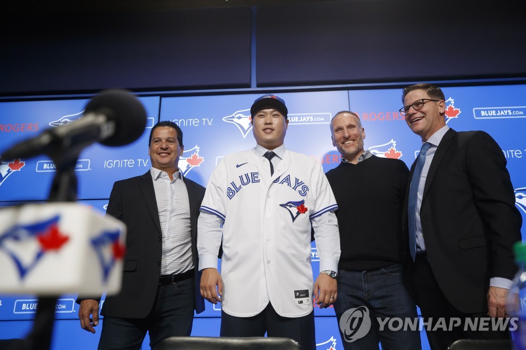 In this Canadian Press photo via the Associated Press from Dec. 27, 2019, South Korean pitcher Ryu Hyun-jin (2nd from L) poses for photos in his new Toronto Blue Jays uniform during his introductory press conference at Rogers Centre in Toronto. Ryu is joined by Blue Jays manager Charlie Montoyo (L), team president Mark Shapiro (2nd from R) and general manager Ross Atkins. (Yonhap)