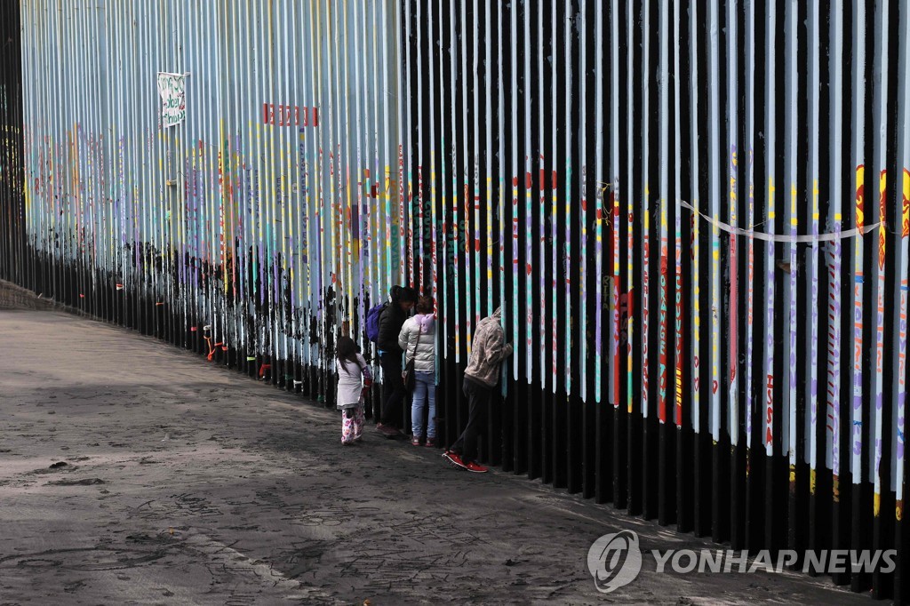 미국-멕시코 국경 펜스 앞에 선 중미 이민자들