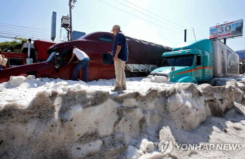 2019년 6월 30일 멕시코 할리스코주 과달라하라 시내에서 주민들이 얼음더미에 파묻힌 트럭들을 살피고 있다. [AFP=연합뉴스]