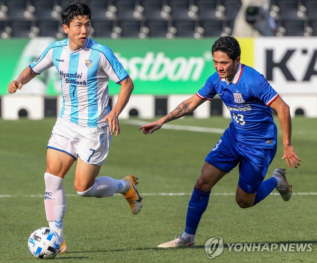 In this AFP photo, Kim In-sung of Ulsan Hyundai FC (L) takes the ball past Qian Jiegei of Shanghai Shenhua during their Group F match at the Asian Football Confederation Champions League at Jassim bin Hamad Stadium in Doha on Dec. 3, 2020. (Yonhap)
