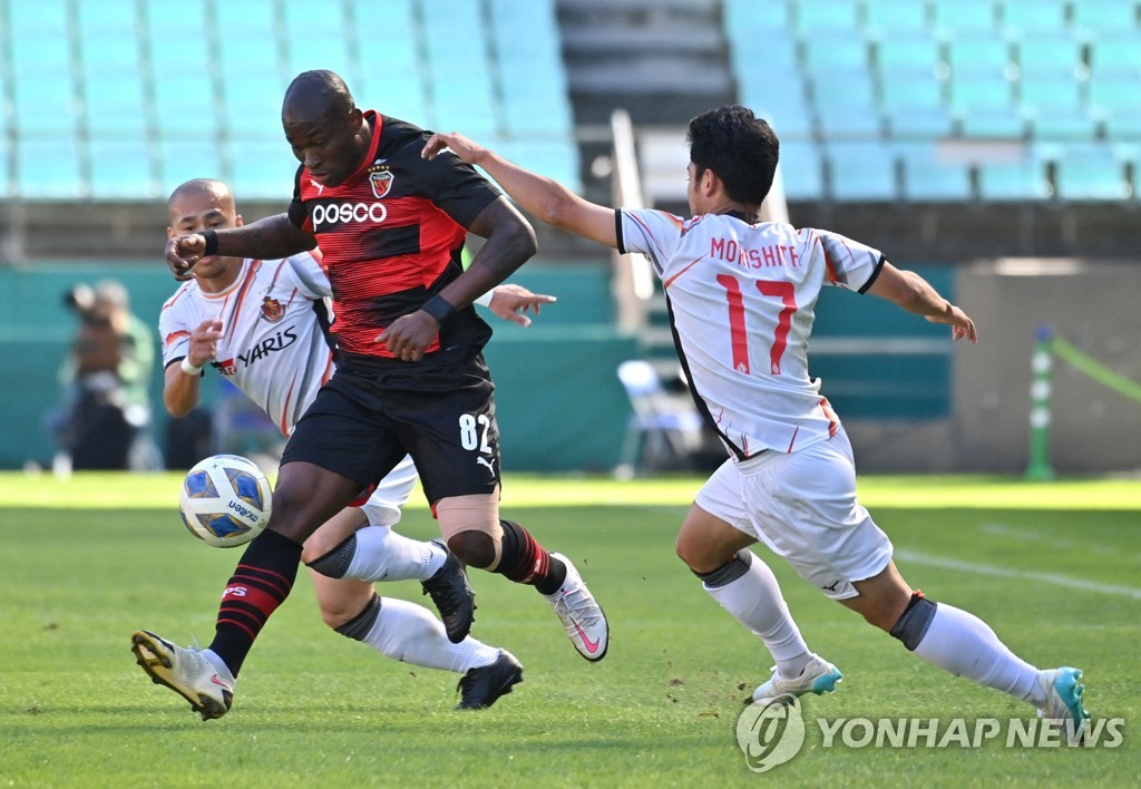 In this AFP photo, Manuel Palacios of Pohang Steelers (C) tries to dribble past Ryoya Morishita of Nagoya Grampus (R) during the clubs' quarterfinal match at the Asian Football Confederation Champions League at Jeonju World Cup Stadium in Jeonju, 240 kilometers south of Seoul, on Oct. 17, 2021. (Yonhap)