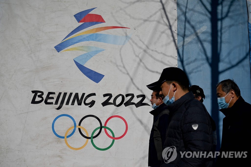 This AFP file photo from Dec. 1, 2021, shows people walking past the logo for the 2022 Beijing Winter Olympics at Shougang Park in Beijing. (Yonhap)