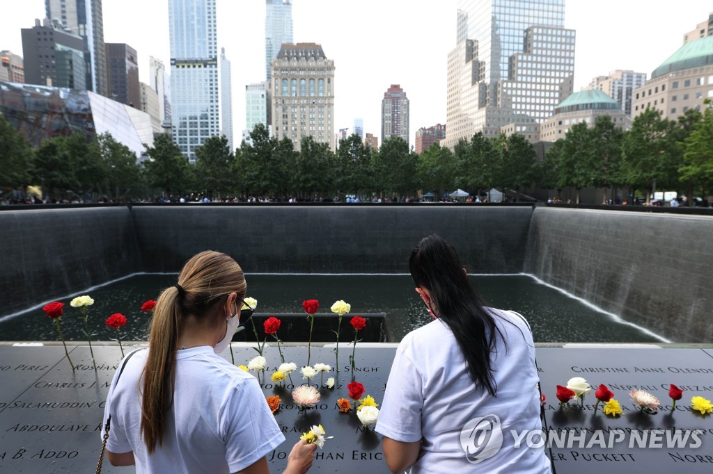 뉴욕 9·11 추모식에서 마스크를 쓰고 희생자 이름 위에 헌화하는 시민들