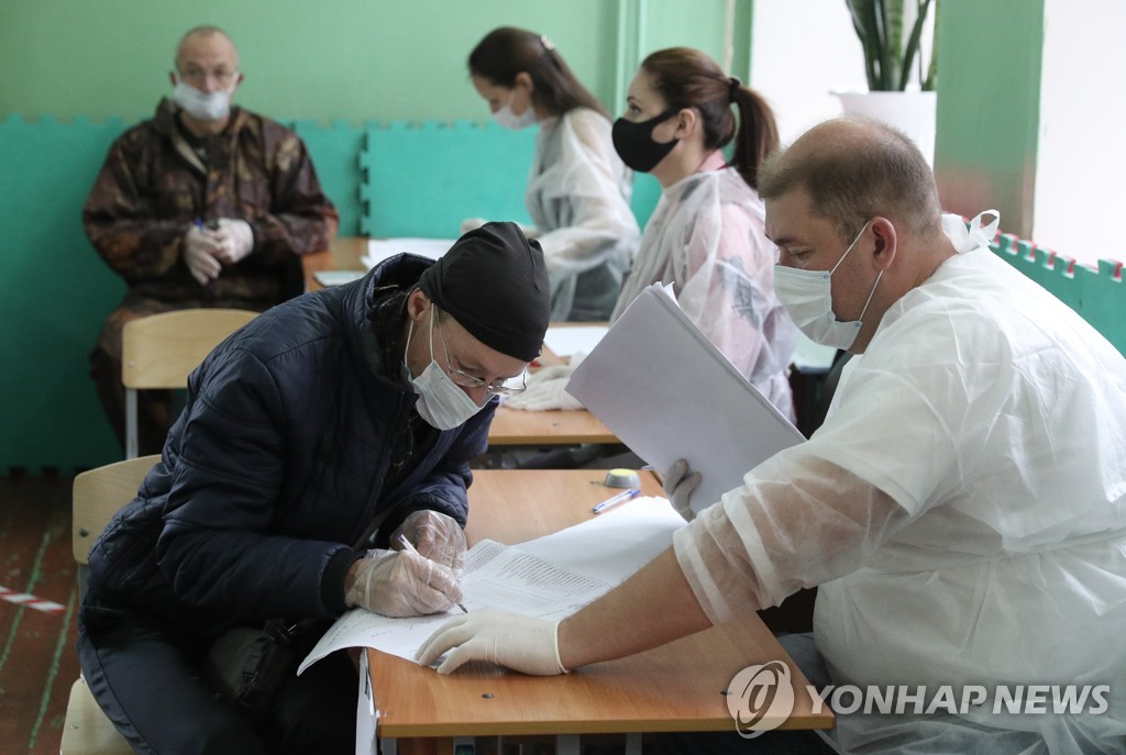 (타스=연합뉴스) 19일 모스크바 인근 트베리주의 투표소에서 마스크를 낀 한 유권자가 투표 등록을 하고 있다.
