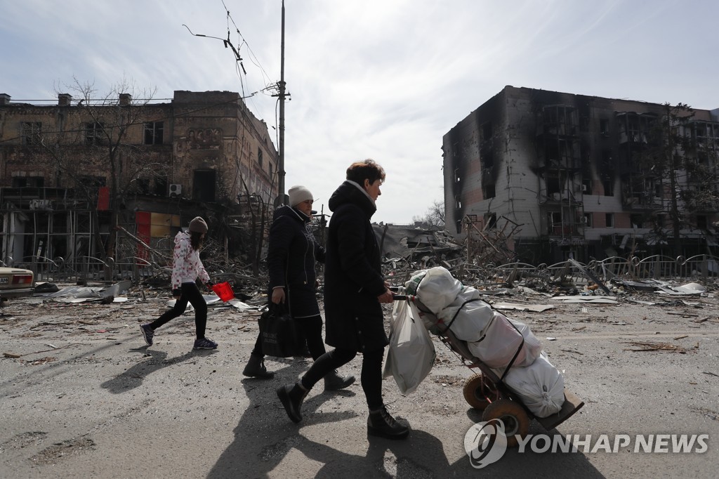 10일(현지시간) 우크라이나 남부 마리우폴에서 파괴된 건물 부근을 지나가는 주민들[신화=연합뉴스 자료사진]