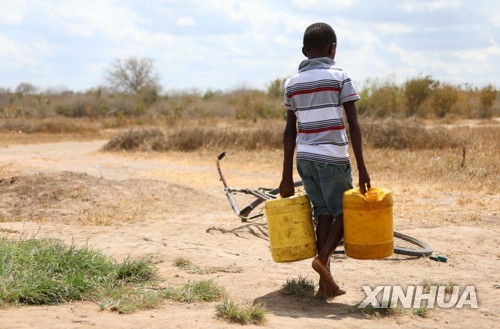 케냐서 물 양동이를 들고 걸어가는 소년