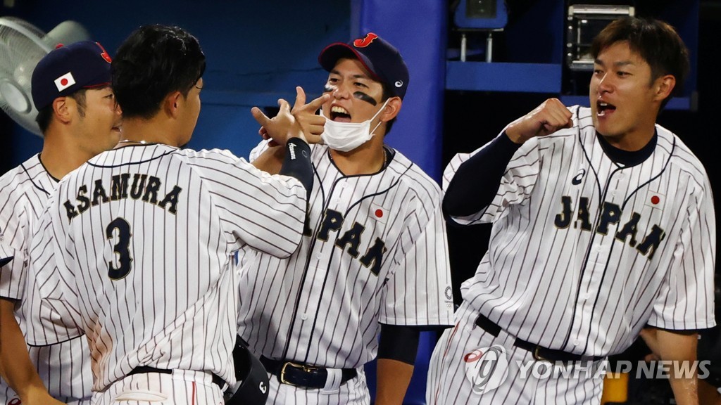 In this Reuters photo, Hideto Asamura of Japan (L) is greeted by teammates after scoring a run against the United States in the bottom of the fifth inning of the teams' second-round game at the Tokyo Olympic baseball tournament at Yokohama Stadium in Yokohama, Japan, on Aug. 2, 2021. (Yonhap)