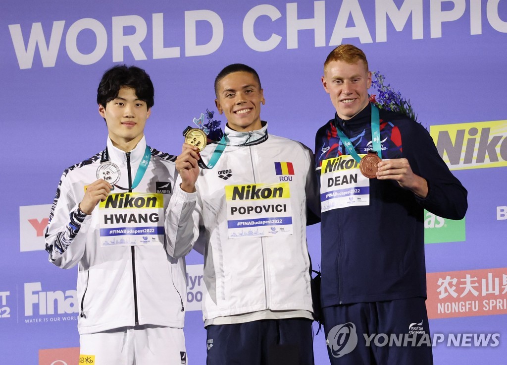 In this Reuters photo, Hwang Sun-woo of South Korea (L) celebrates on the podium after winning silver in the men's 200m freestyle at the FINA World Championships at Duna Arena in Budapest on June 20, 2022. Hwang stands next to the gold medalist, David Popovici of Romania (C), and the bronze medalist, Tom Dean of Britain. (Yonhap)