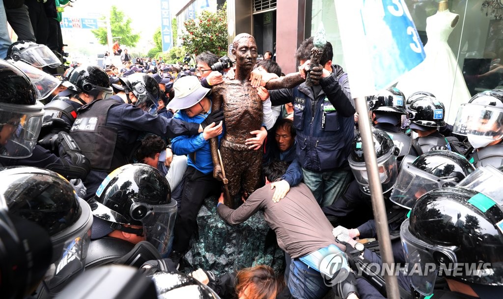 市民団体メンバーを像から引き離そうとする警察＝１日、釜山（聯合ニュース）