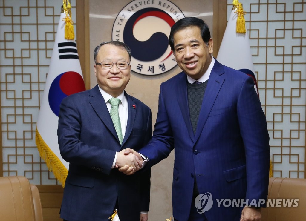 South Korea's National Tax Service Commissioner Han Sung-hee (L) shakes hands with his Cambodian counterpart Kong Vibol at the NTS office in central Seoul on Jan. 8, 2019, in this photo provided by the NTS. (Yonhap)
