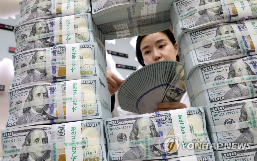 In the file photo, an official inspects U.S. dollar bills at a Seoul bank. (Yonhap)