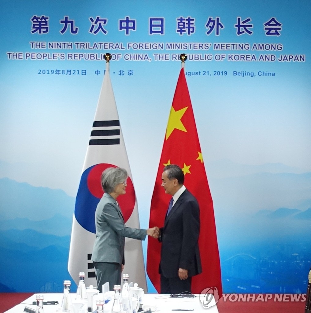 握手を交わす康氏（左）と王氏（北京特派員共同取材団）＝２０日、北京（聯合ニュース）