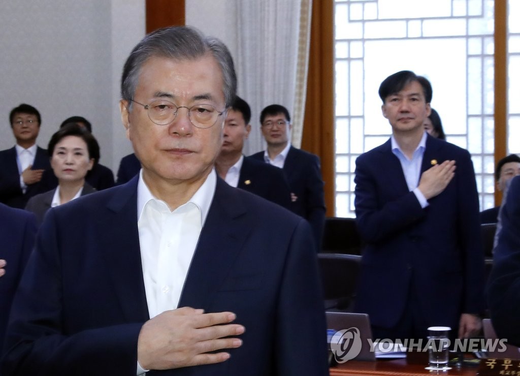 In this file photo, dated Oct. 8, 2019, President Moon Jae-in (front) salutes the national flag, with Justice Minister Cho Kuk (R) doing likewise behind him, at the start of a Cabinet meeting at Cheong Wa Dae. (Yonhap) 