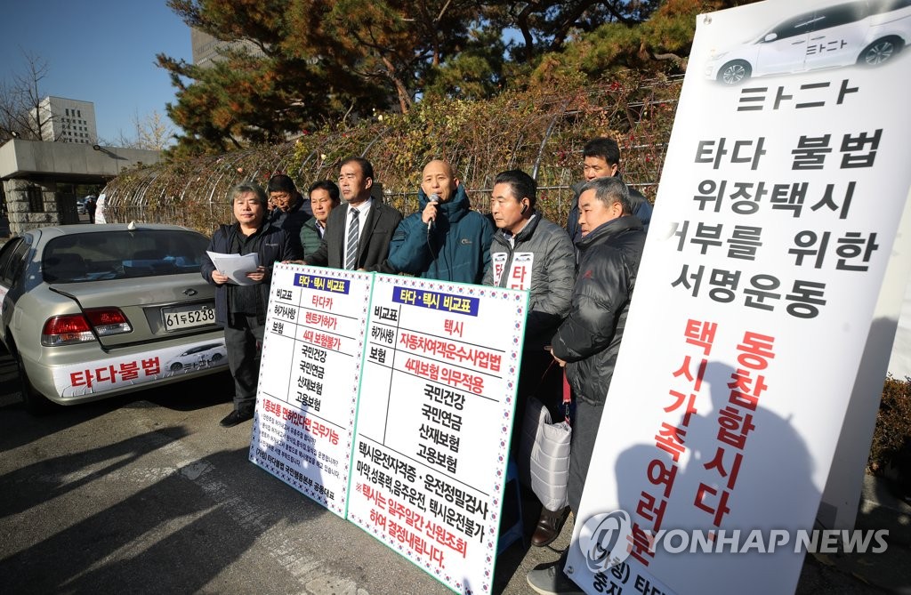 A group of taxi drivers stages a rally in front of Seoul Central District Court, calling for the suspension of the Tada service, on Dec. 2, 2019. (Yonhap)