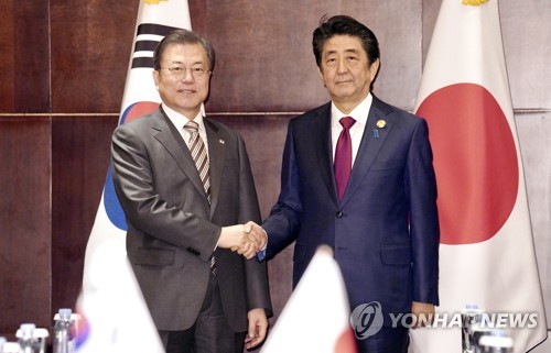 昨年１２月に中国で行われた韓日首脳会談で握手を交わす文大統領（左）と安倍氏（資料写真）＝（聯合ニュース）
