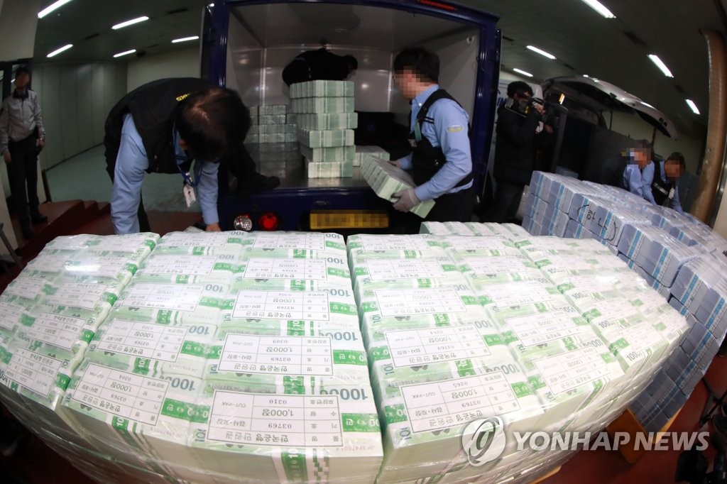 In the undated file photo, officials at a Seoul branch of the Bank of Korea prepare new banknotes for their release. (Yonhap)