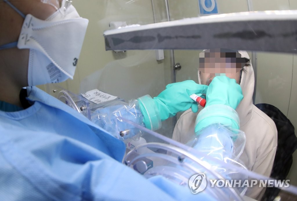 A health worker collects a sample of saliva for a novel coronavirus test at Seoul National University Boramae Medical Center in Seoul on March 16, 2020. (Yonhap)