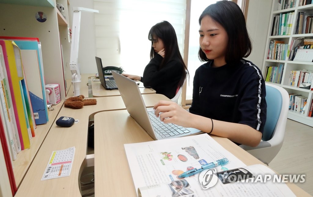 Twin sisters Park Ha-neul and Park Ga-eul, who are both seniors at middle schools, take online classes at their home in the western Seoul ward of Yangcheon on April 9, 2020. (Yonhap)