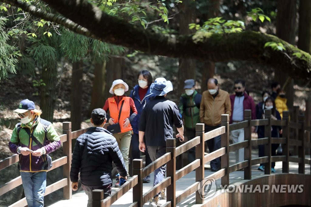 Citizens wearing face masks walk in a park in Busan on April 26, 2020. (Yonhap)