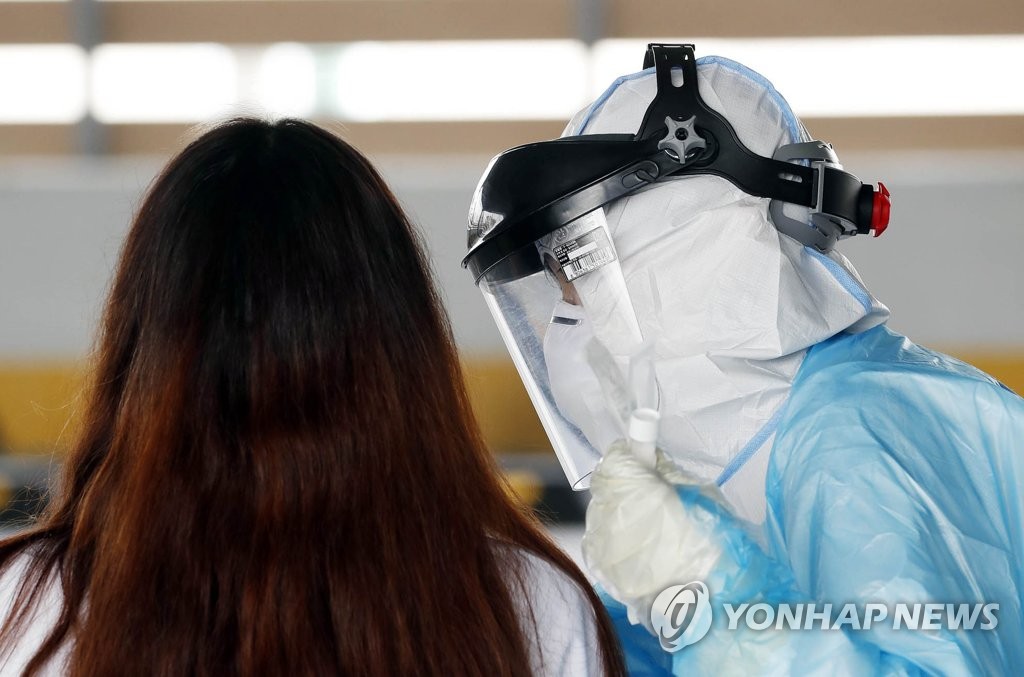 A health worker tests a woman for coronavirus in an outdoor screening center in Gwangju, 329 kilometers southwest of Seoul on May 14, 2020, as Itaewon-related cases grew in this photo, provided by the Buk-gu office in Gwangju. (PHOTO NOT FOR SALE) (Yonhap)