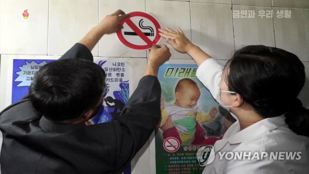 North Korean officials place a nonsmoking sticker on a wall, in this photo captured from the North's Korean Central TV on May 31, 2020. (For Use Only in the Republic of Korea. No Redistribution) (Yonhap)