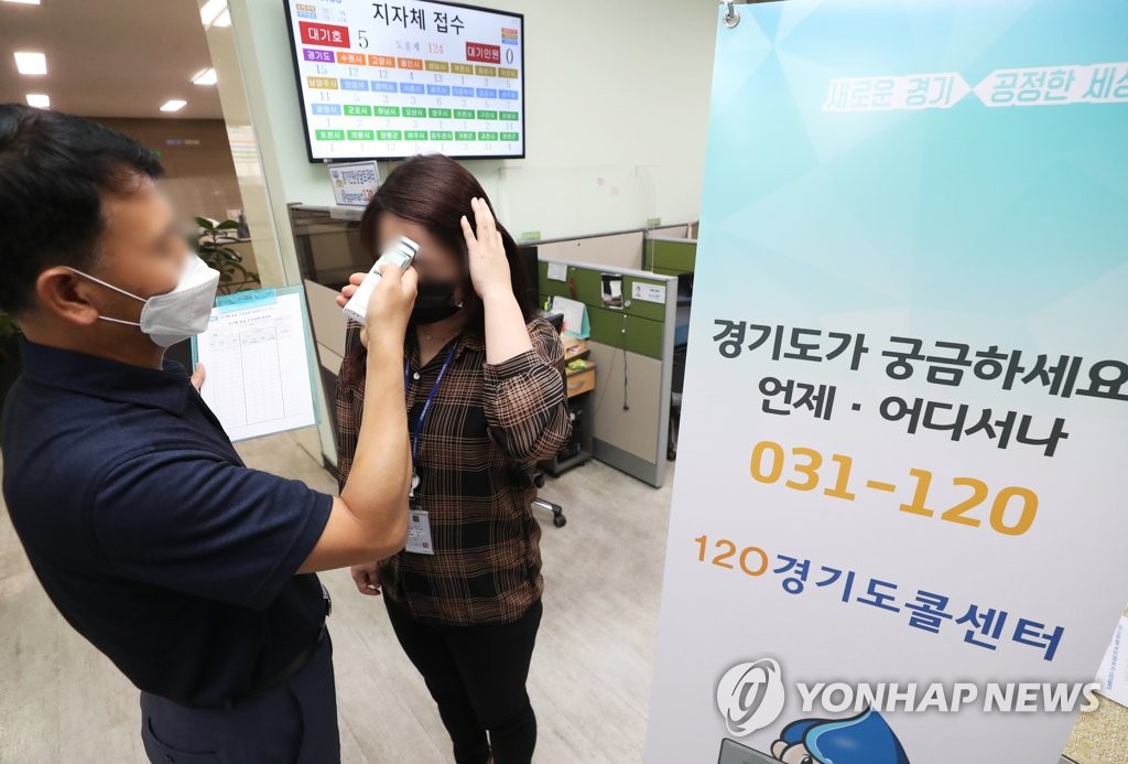 An official working at a call center of the Gyeonggi provincial government in Suwon, south of Seoul, has her temperature checked on June 2, 2020, when she arrives at the office. (Yonhap)