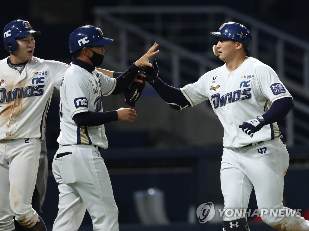 Na Sung-bum of the NC Dinos (R) is greeted at the home plate by teammate Park Min-woo (L) and first base coach Lee Jong-wook after hitting a two-run home run against the SK Wyverns in a Korea Baseball Organization regular season game at Changwon NC Park in Changwon, 400 kilometers southeast of Seoul. (Yonhap)