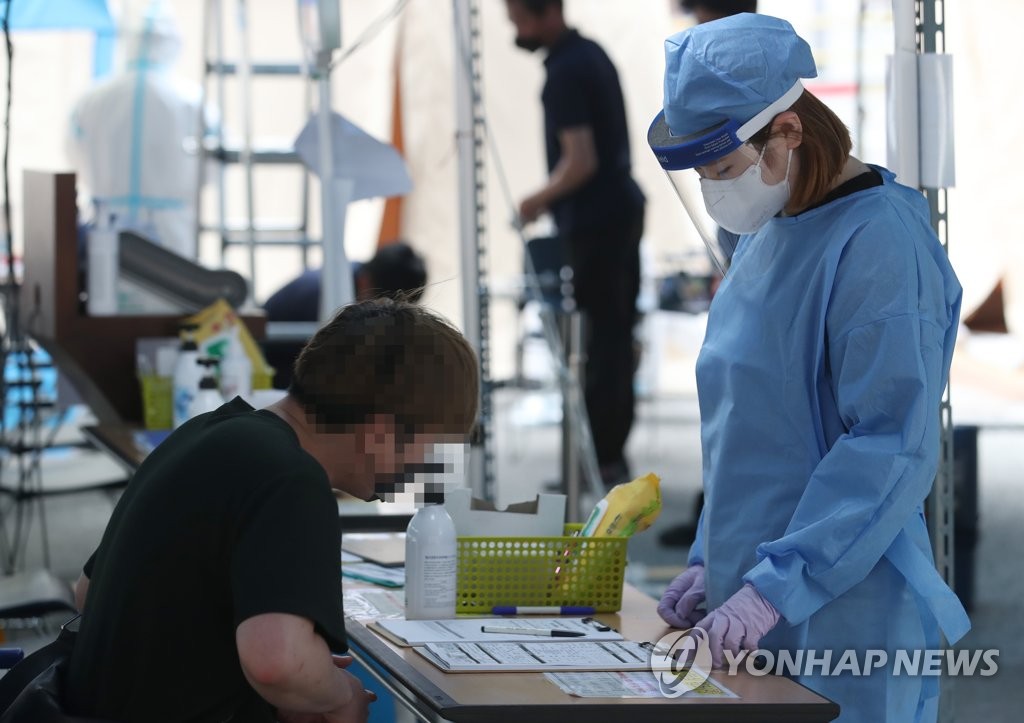 A visitor fills out documents before receiving a new coronavirus test at a makeshift clinic in southern Seoul on June 12, 2020. (Yonhap)