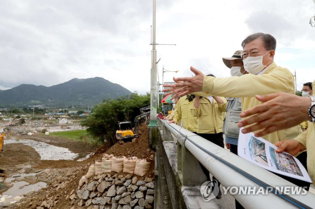 President Moon Jae-in (R) looks around a river bank and road, devastated by torrential rains, in Gurye, South Jeolla Province on Aug. 12, 2020. (Yonhap)