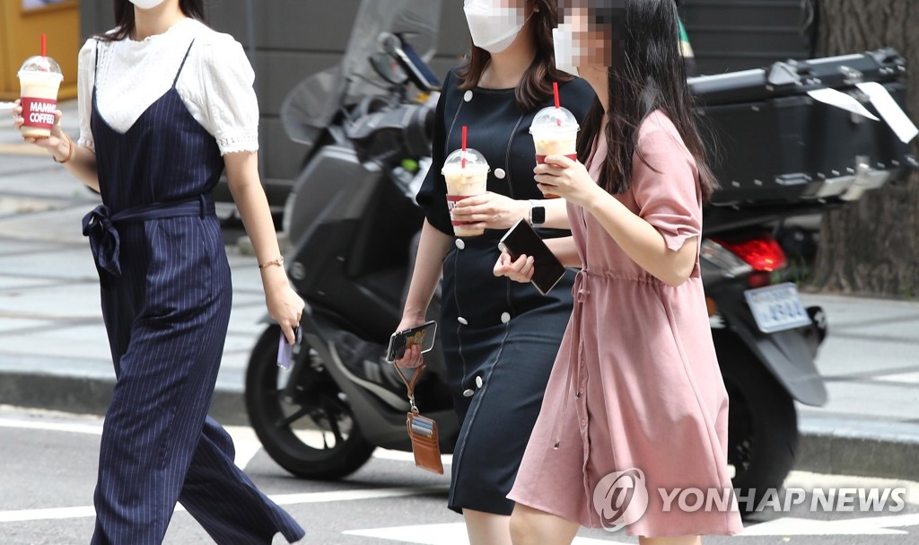 People walk while holding takeout coffee at lunch time on a street in Seoul on Sept. 1, 2020, as toughened social distancing guidelines are enforced to prevent the virus spread. (Yonhap)