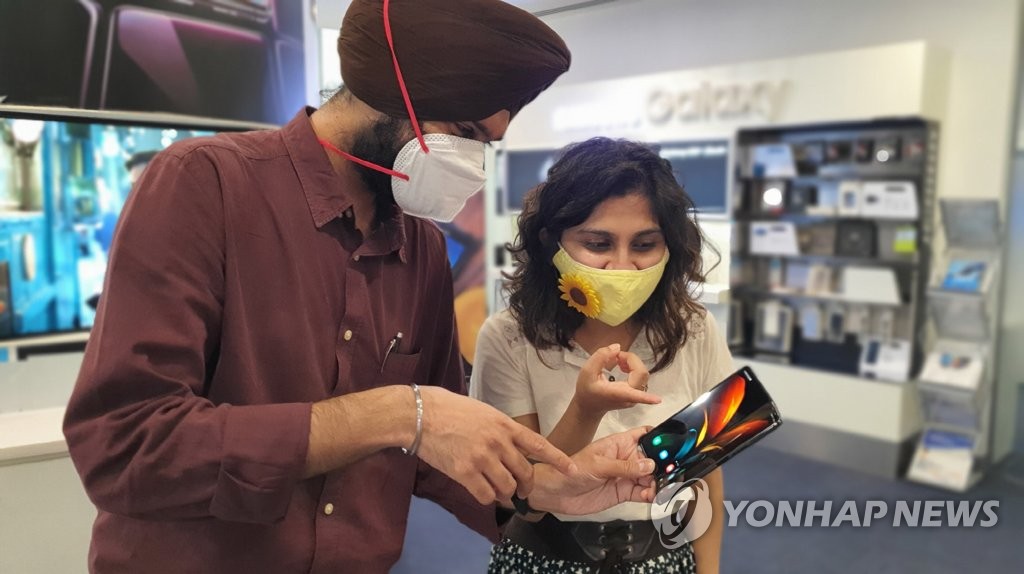 This photo provided by Samsung Electronics Co. on Sept. 18, 2020, shows Indian consumers looking at the company's Galaxy Z Fold2 smartphone at a store in Gurugram, India. (PHOTO NOT FOR SALE) (Yonhap)