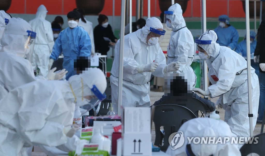 This photo taken on Nov. 25, 2020, shows health workers clad in protective gear giving a citizen a COVID-19 test at a makeshift virus testing clinic in Ulsan, 414 kilometers southeast of Seoul. (Yonhap)