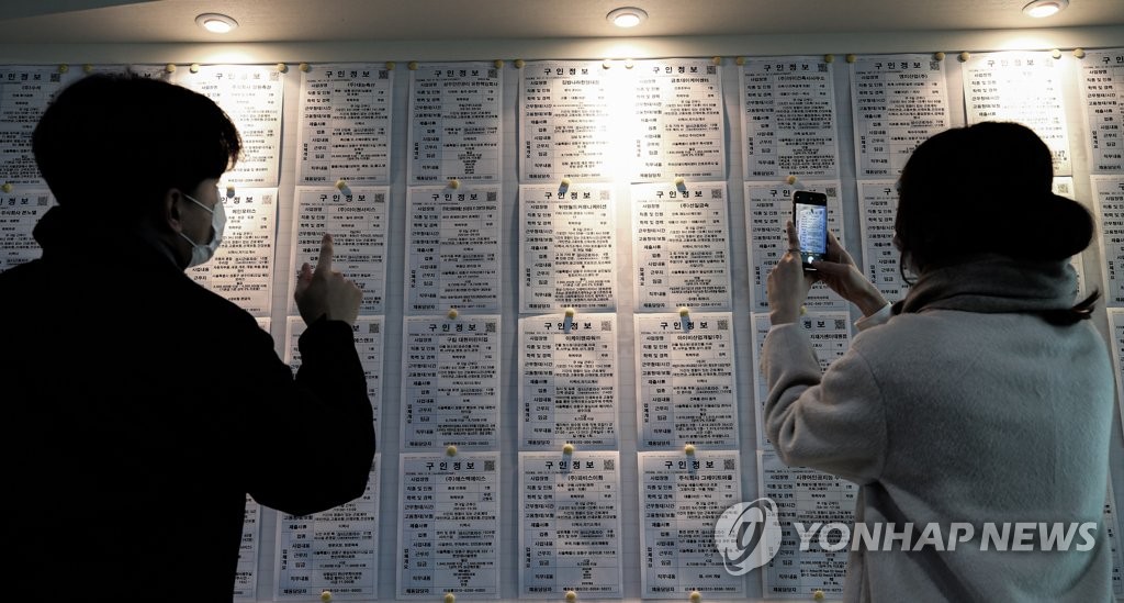 This file photo, taken Jan. 13, 2021, shows people looking at job opening information at an employment arrangement center in Seoul. (Yonhap)